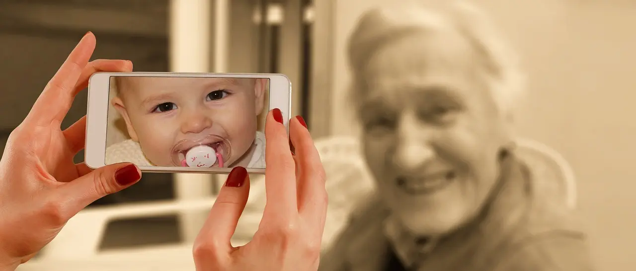 En kvinde glæder sig over et babyfoto på en telefon.