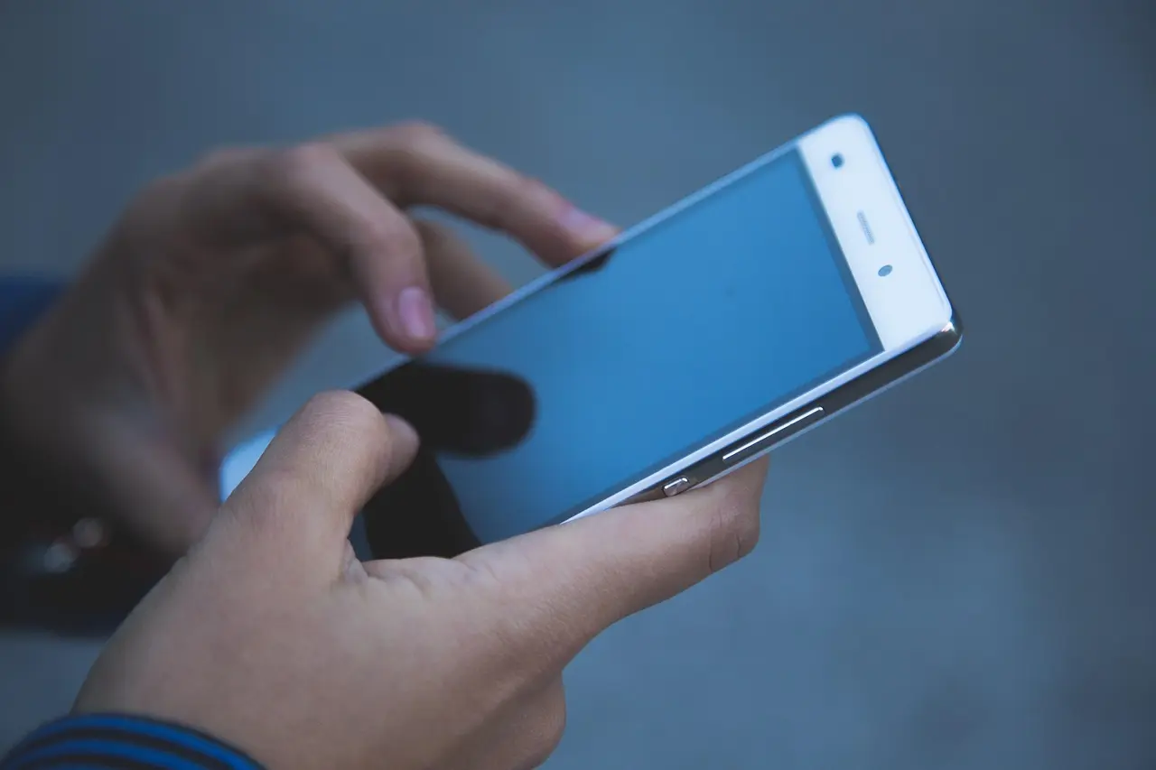 Hænder holder en smartphone, klar til næste tryk.